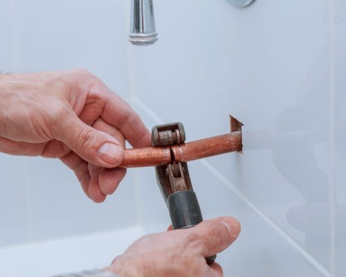 hand of working cutting copper pipe plumbing